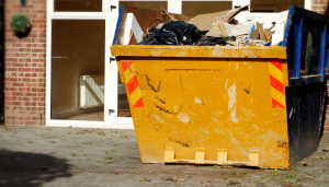 container empli de déchets devant une maison vide